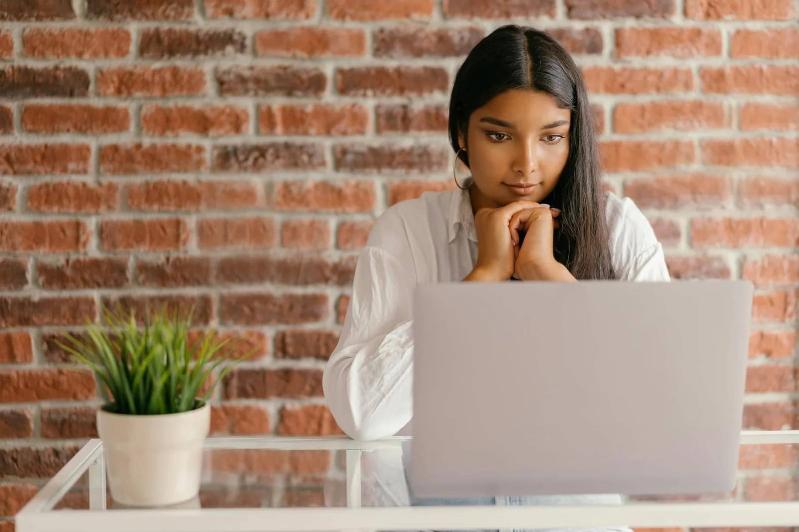 a girl in white long sleeve shirt sitting in front of laptop