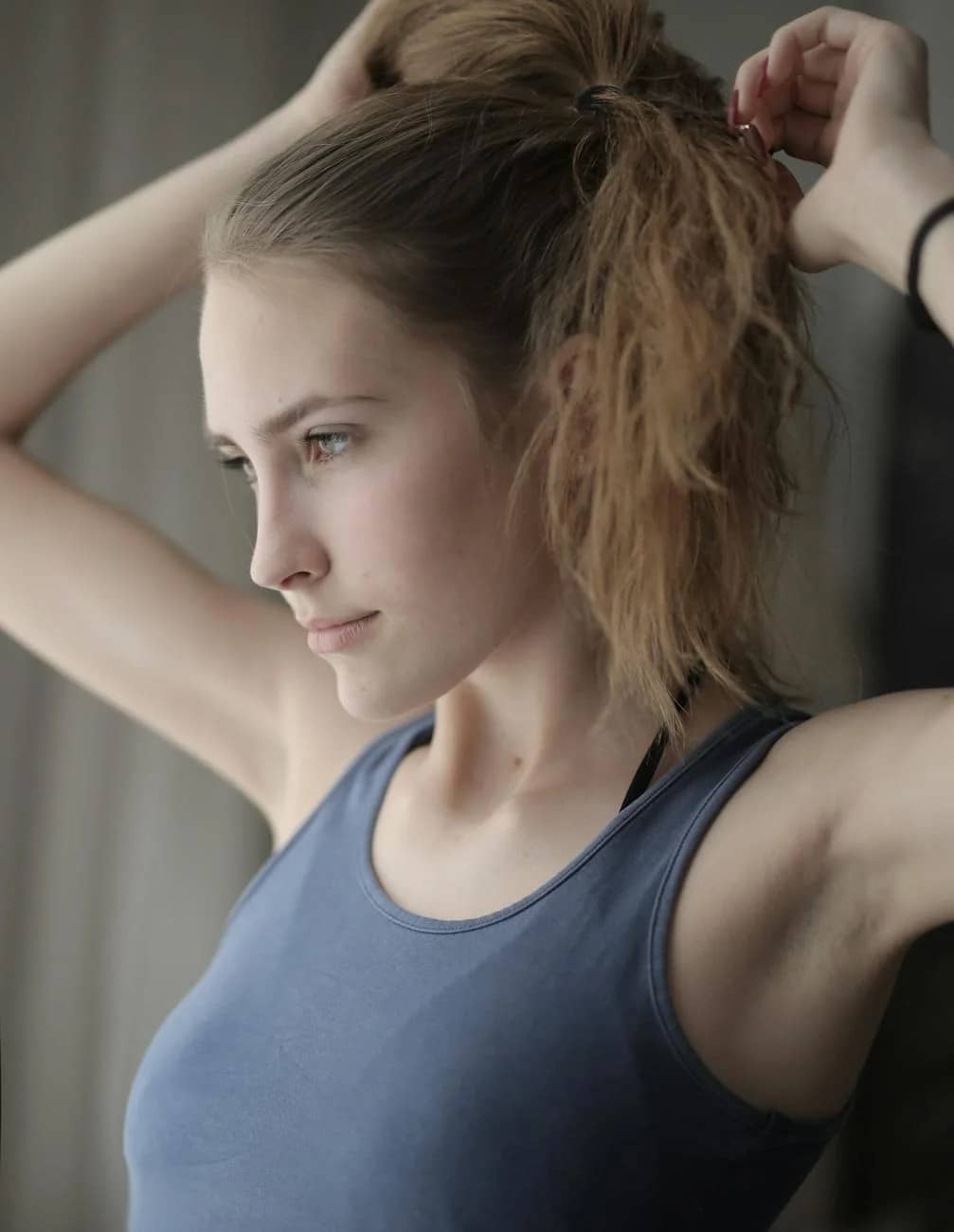 beautiful young woman making ponytail raising arms up