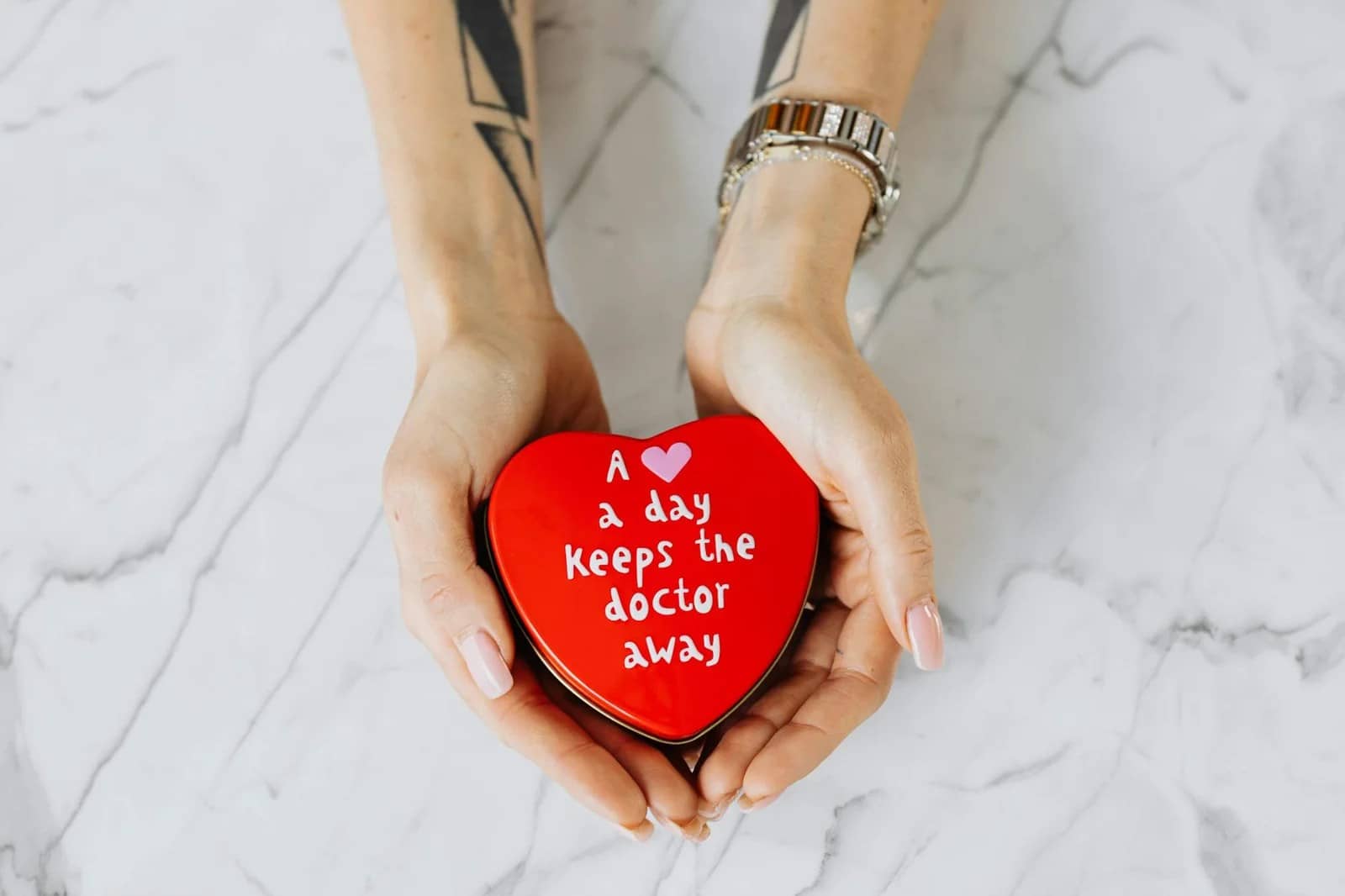 person holding red heart shape container -Herbs for fat loss