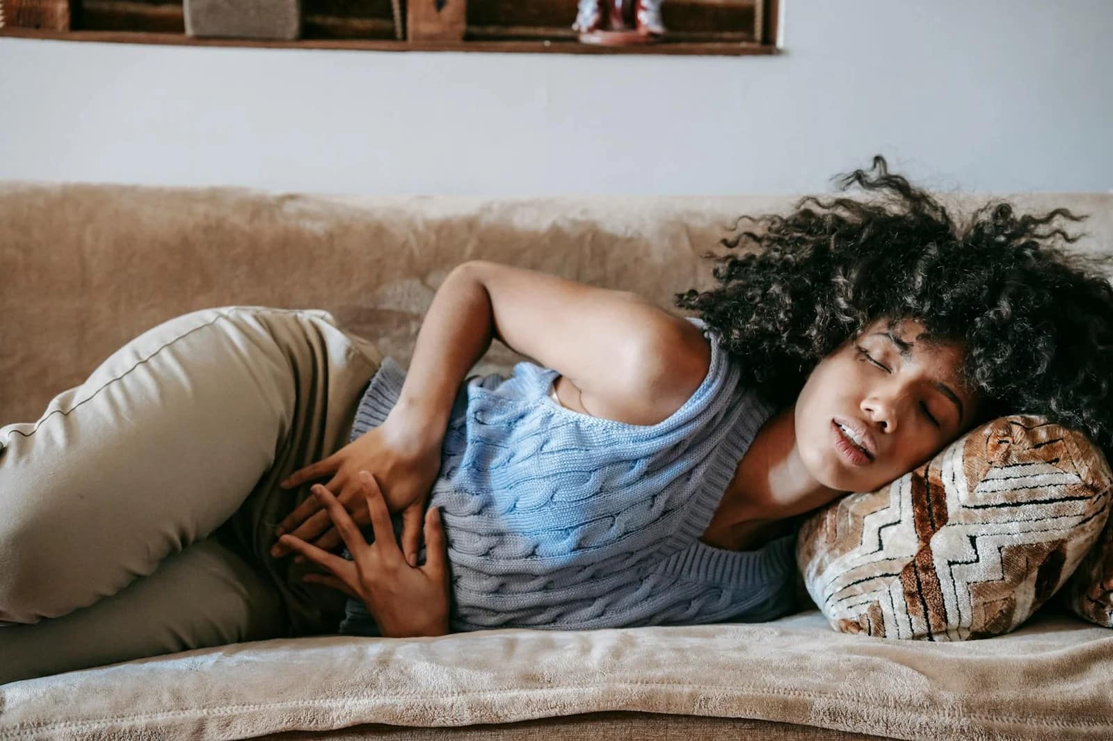 woman suffering from a stomach pain lying down on couch - Menopause symptoms