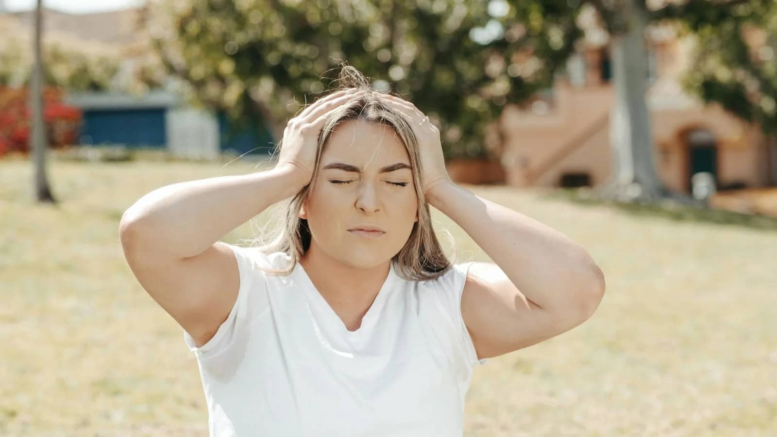 a woman holding her head while eyes closed